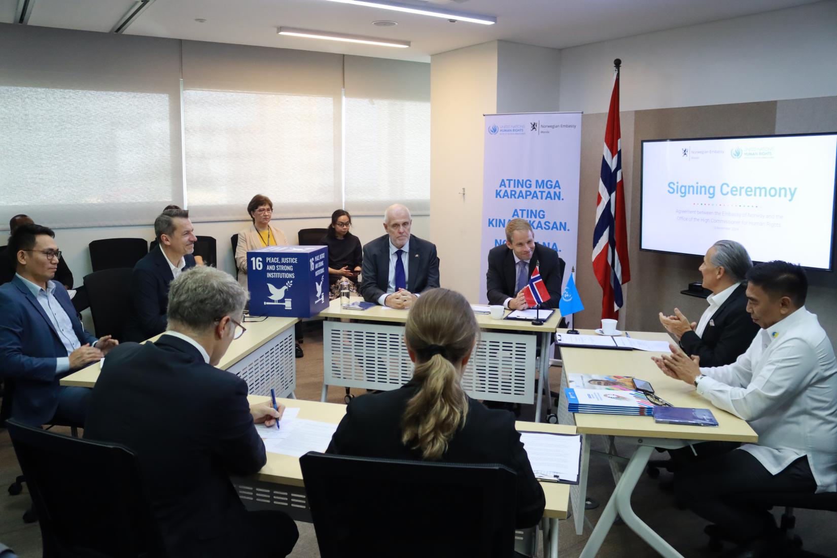 Eight people sit at tables arranged in a diamond formation; four people on the left side are representatives from the Norwegian Embassy, while of the people on the right side of the photo, three are from the United Nations and one from the Philippine Commission on Human Rights