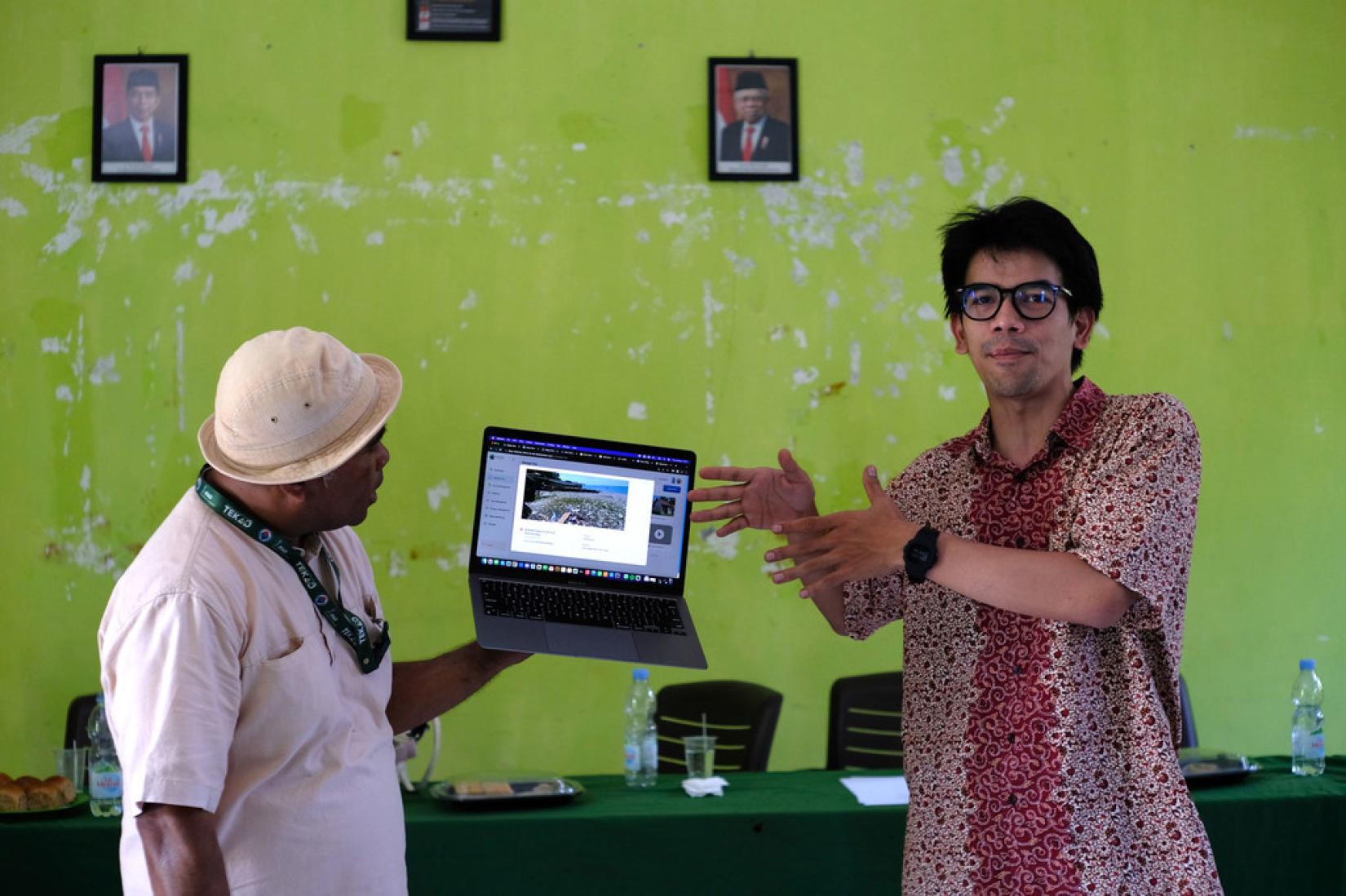 Two village leaders in Indonesia testing STRIVE, a UNDP-backed AI tool, in a laptop 