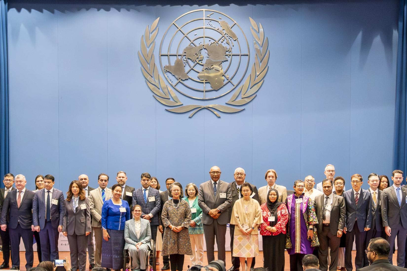 A group of people posing for a photo behind the United Nations logo