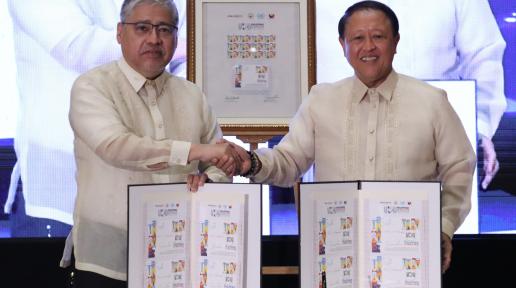 Two men shake hands while displaying stamps